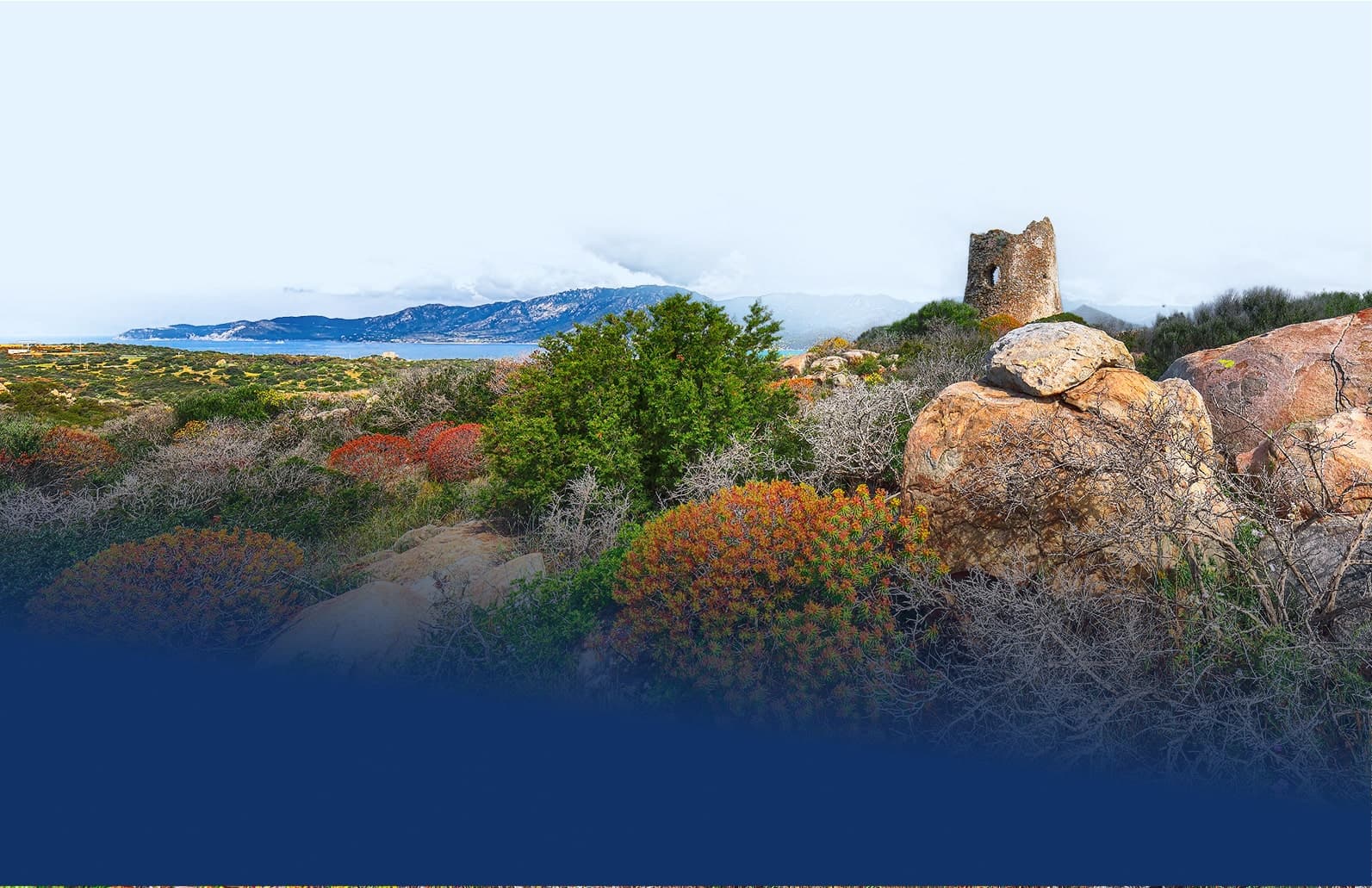 Torretta in pietra tra rocce e macchia mediterranea in Sardegna